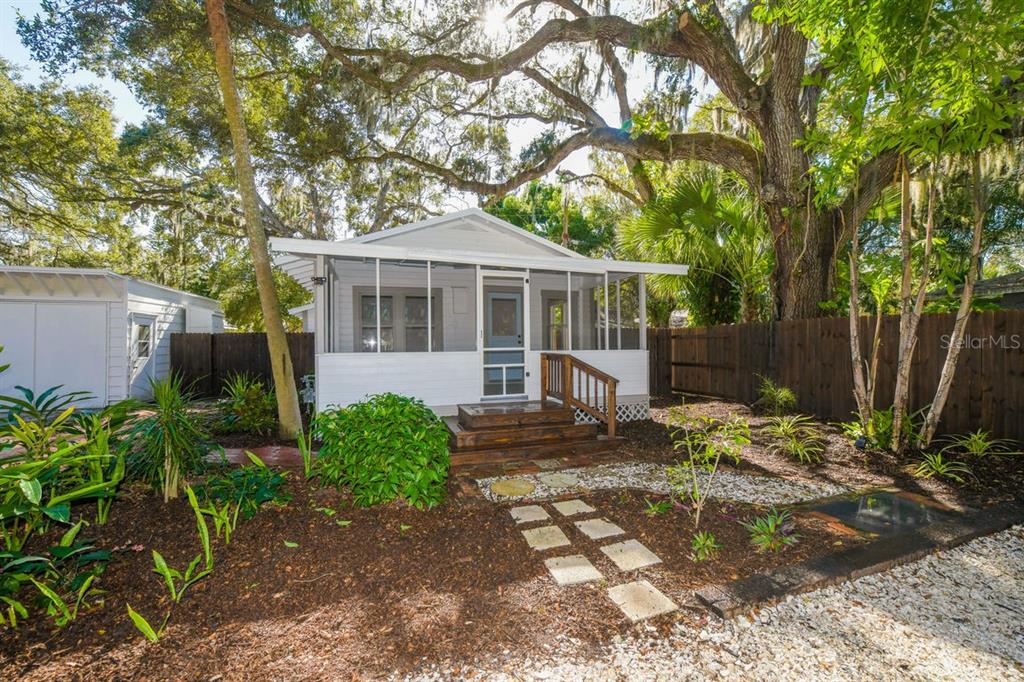 A small, white cottage with a screened-in front porch sits in a landscaped yard — 1230 35TH STREET, SARASOTA, FL