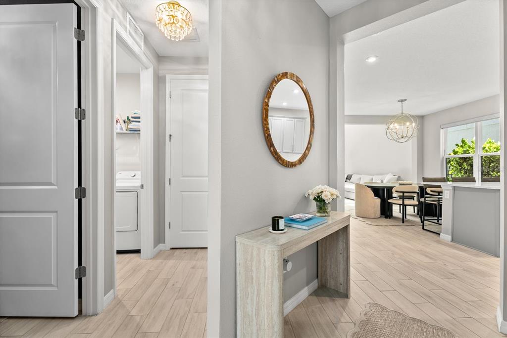 A hallway with light wood-look tile flooring leads to an open-concept dining and living area — 15360 ISLA PALMA LANE, NOKOMIS, FL
