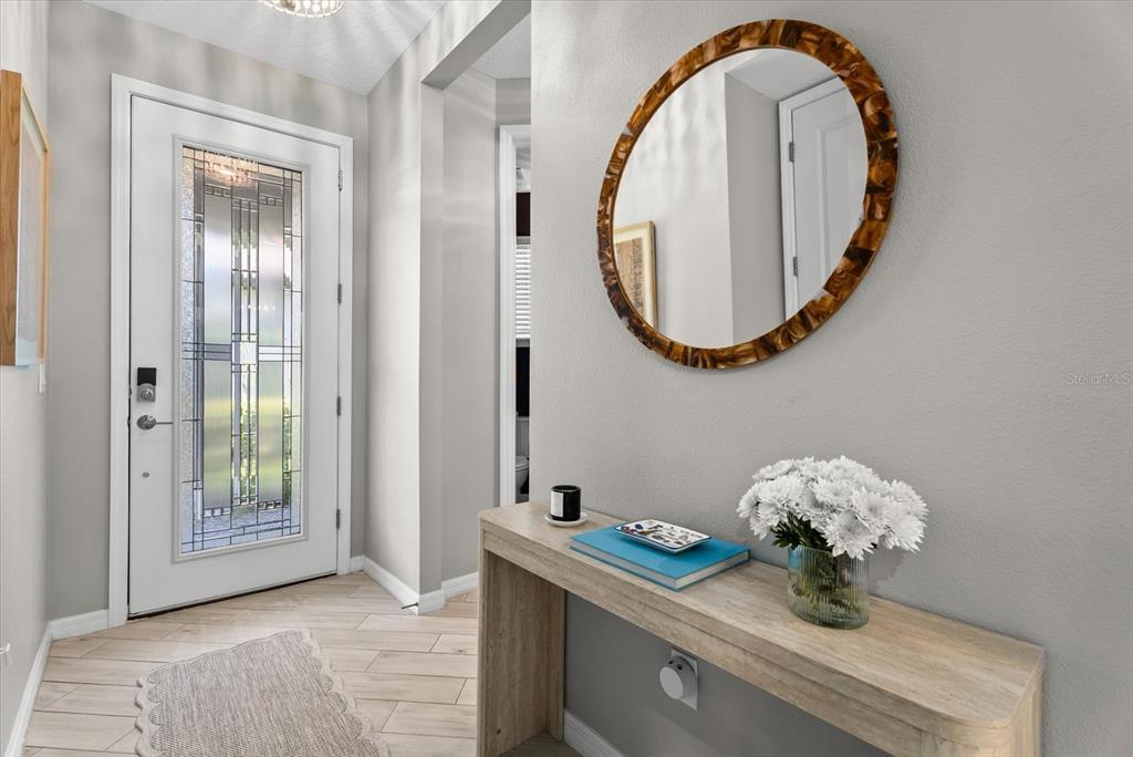 An entryway features a white front door, a console table, and a round decorative mirror — 15360 ISLA PALMA LANE, NOKOMIS, FL