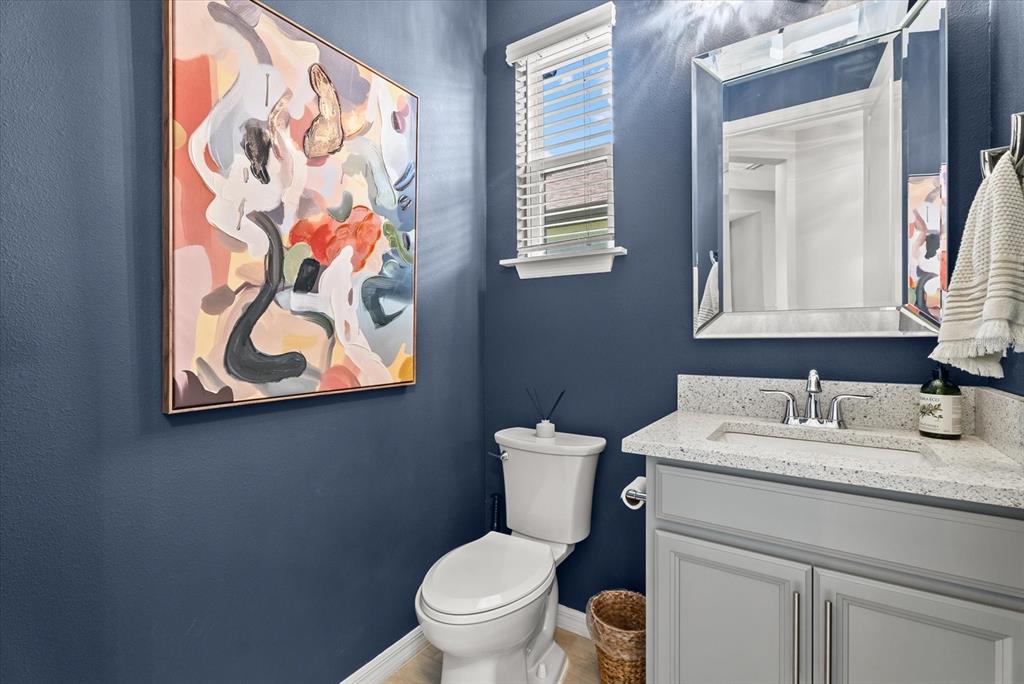 A powder room features dark blue walls, a gray vanity, and a large abstract painting — 15360 ISLA PALMA LANE, NOKOMIS, FL