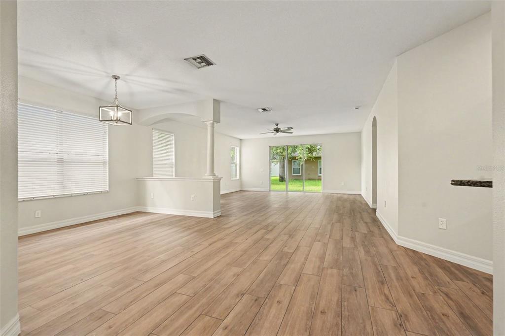 An open-concept living and dining area features light-colored walls, wood-look flooring, and sliding glass doors — 453 WESTCHESTER HILLS LANE, VALRICO, FL