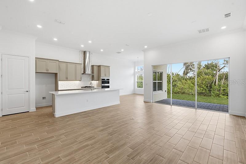 A modern kitchen with light-colored cabinets and an island opens to a spacious living area — 911 SIGNET DRIVE, APOLLO BEACH, FL