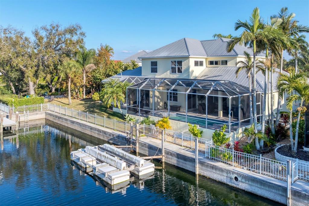 A two-story yellow house with a metal roof, front porch, and a concrete driveway — 4627 BARRACUDA DRIVE, BRADENTON, FL