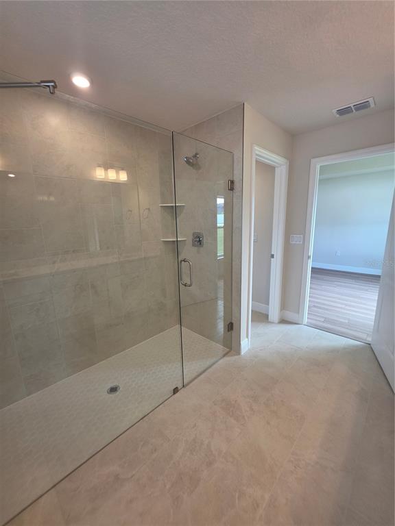 A bathroom features a walk-in glass shower with light-colored tile walls and flooring — 5346 SE 91ST STREET, OCALA, FL