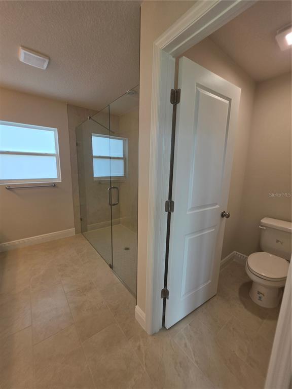 A bathroom features a glass-enclosed walk-in shower, a private toilet room, and light-colored tile flooring — 5346 SE 91ST STREET, OCALA, FL