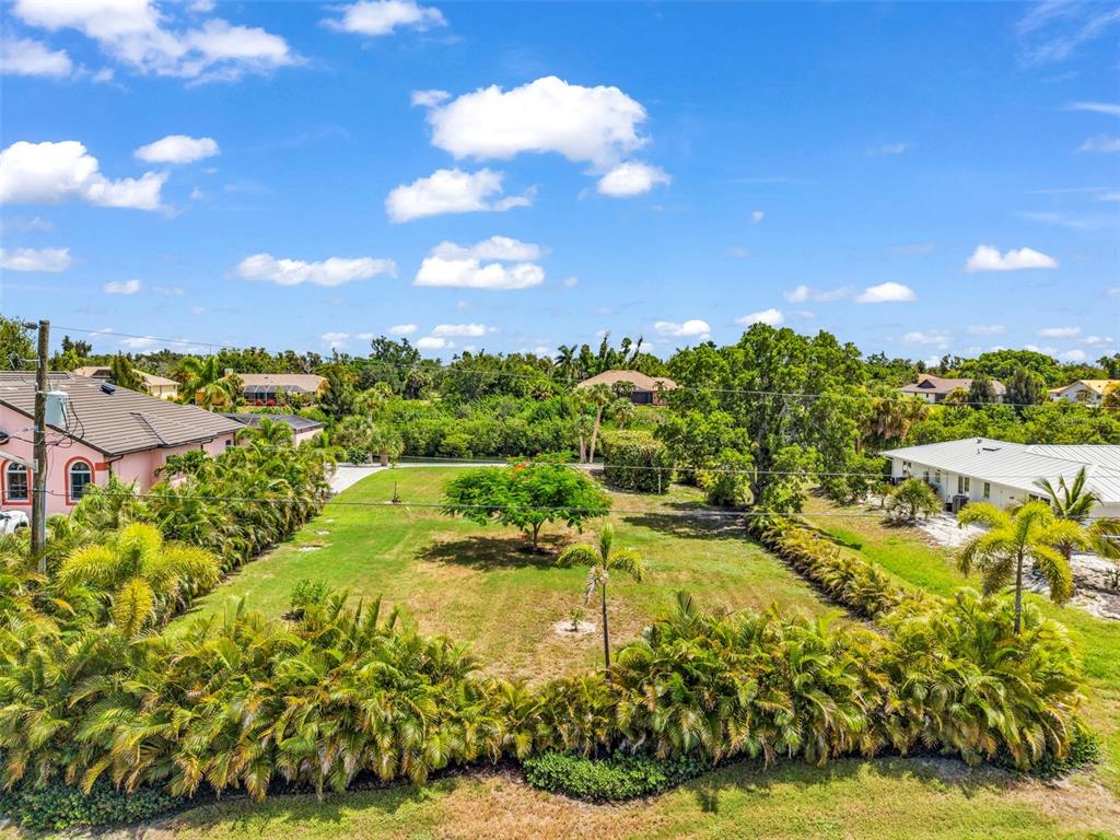 An aerial view shows a grassy vacant lot bordered by palm trees and neighboring houses — Lot 12 CAPSTAN DRIVE, PLACIDA, FL