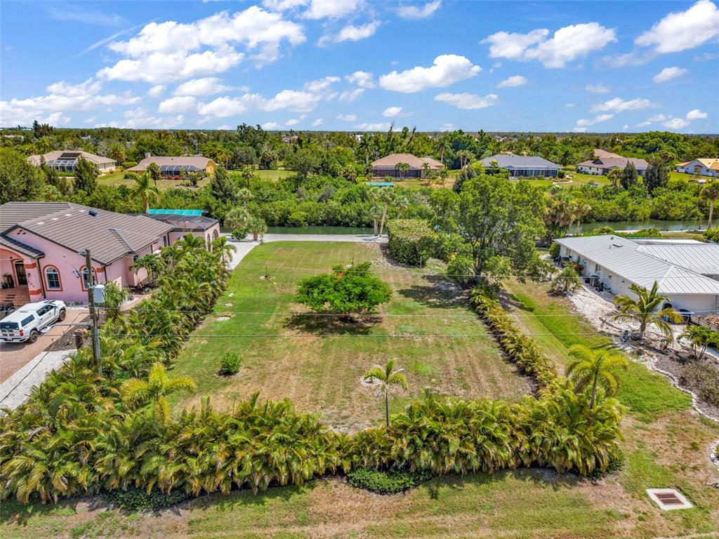 An aerial view shows a vacant rectangular lot bordered by palm trees and neighboring houses — Lot 12 CAPSTAN DRIVE, PLACIDA, FL