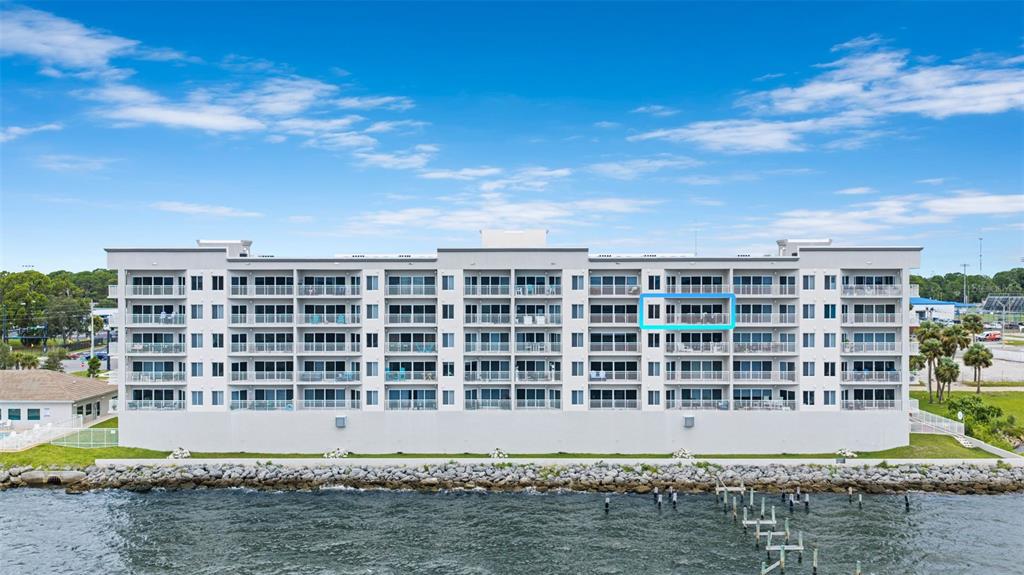 An aerial view of a multi-story apartment building situated along a rocky shoreline — 1805 RIVERSIDE DRIVE UNIT 503, TITUSVILLE, FL