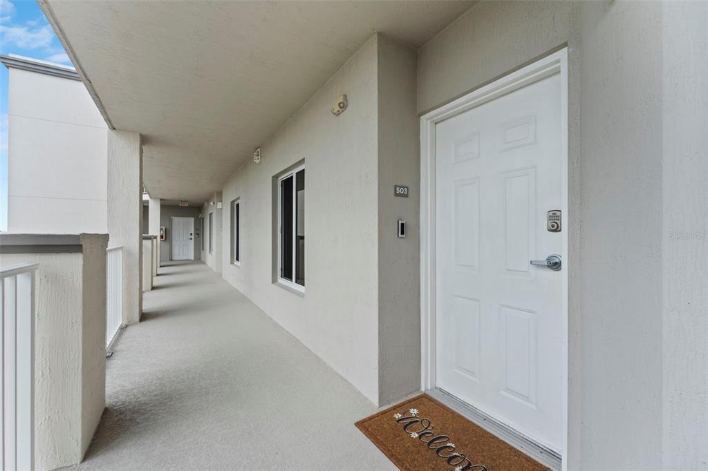 An exterior hallway of an apartment building features a white door labeled 503 — 1805 RIVERSIDE DRIVE UNIT 503, TITUSVILLE, FL