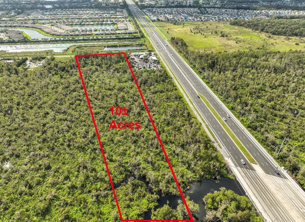An aerial view shows a rectangular plot of undeveloped land outlined in red beside a highway — 11632 BILL TUCKER ROAD, WIMAUMA, FL