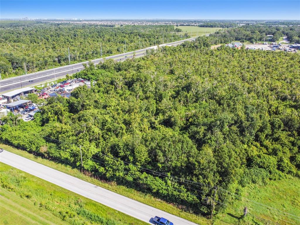 An aerial view shows a dense, wooded lot situated between two paved roads — 11632 BILL TUCKER ROAD, WIMAUMA, FL