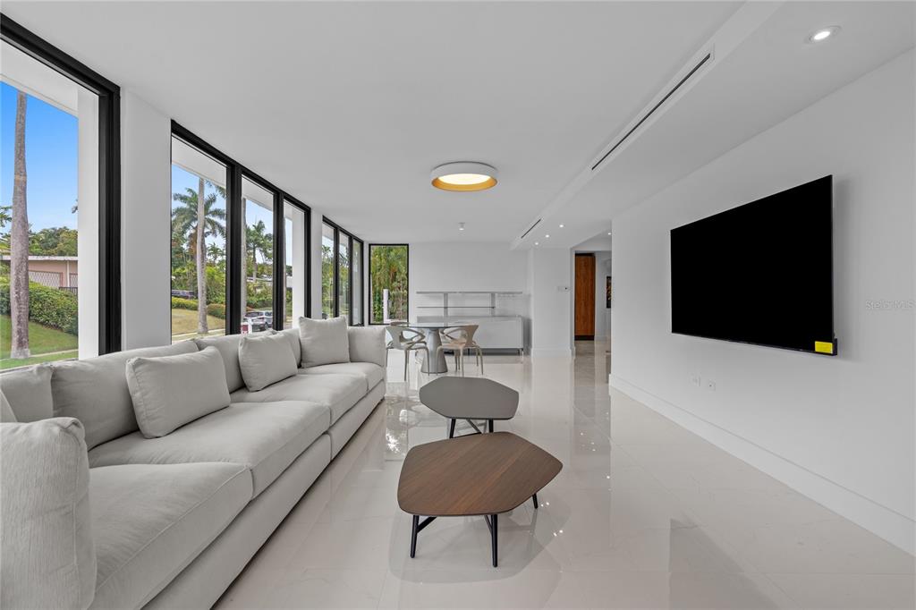 A modern living room features a large grey sofa, two coffee tables, and floor-to-ceiling windows — D-1 SUN VALLEY, GUAYNABO, PR