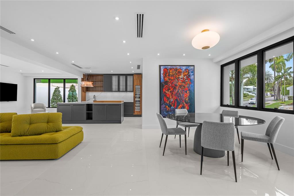 An open-concept living and dining area with a modern kitchen, yellow sofa, and large artwork — D-1 SUN VALLEY, GUAYNABO, PR