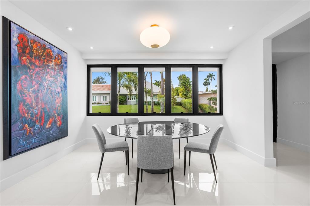 A dining room with a glass table, gray chairs, large windows, and a colorful wall painting — D-1 SUN VALLEY, GUAYNABO, PR
