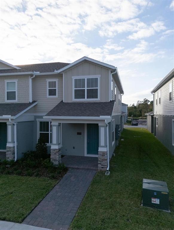 An open-concept living area features light wood-look flooring, a kitchen island, and a carpeted staircase — 13193 CALMING BREEZE WAY, WINTER GARDEN, FL