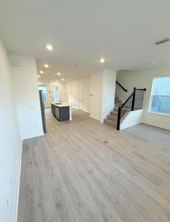A modern kitchen features white upper cabinets, gray lower cabinets, stainless steel appliances, and an island — 13193 CALMING BREEZE WAY, WINTER GARDEN, FL