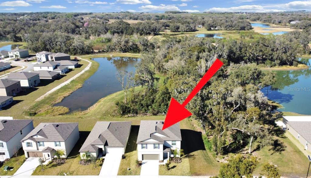 An aerial view shows a suburban house with a red arrow pointing to its roof — 36385 FLATS STREET, ZEPHYRHILLS, FL