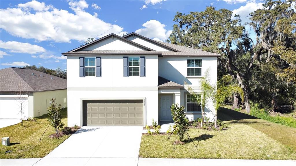 A two-story house with a white exterior, a two-car garage, and blue window shutters — 36385 FLATS STREET, ZEPHYRHILLS, FL