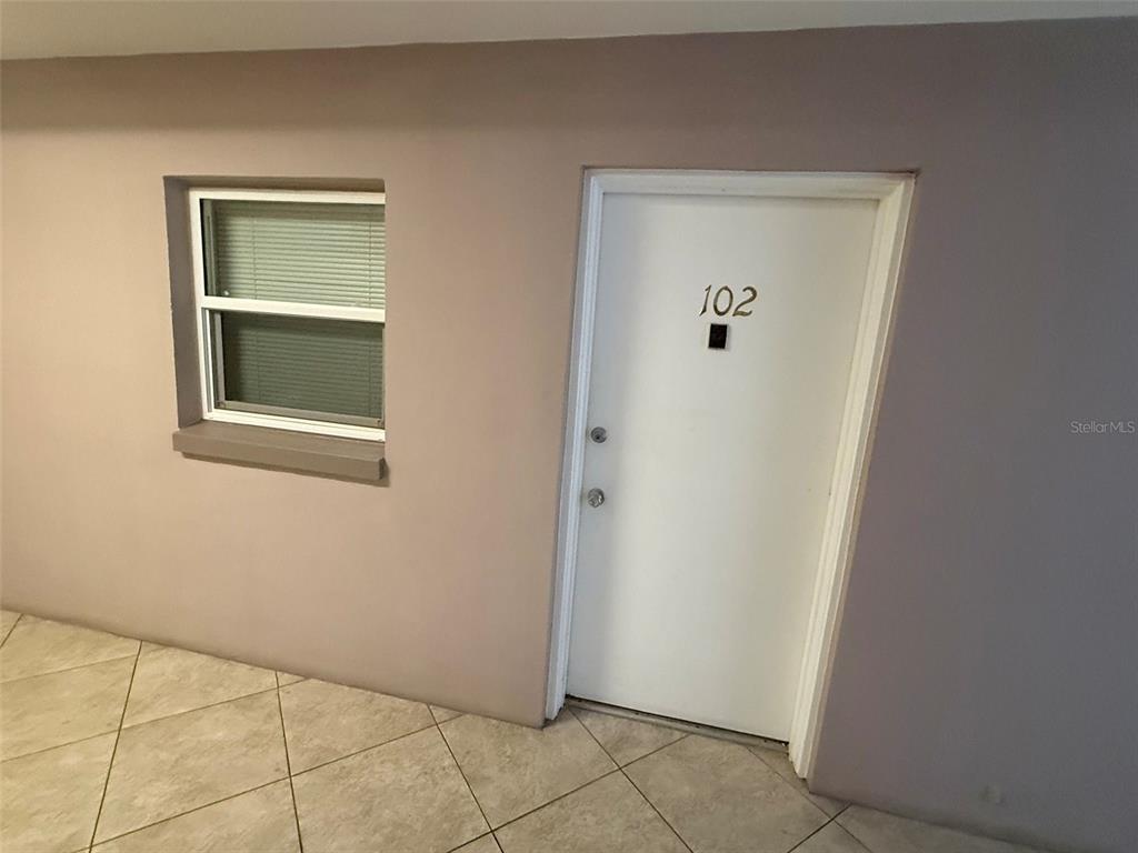An interior view shows a living area with wood-look flooring leading to an adjacent room — 3100 HARBOR BOULEVARD UNIT 102, PORT CHARLOTTE, FL