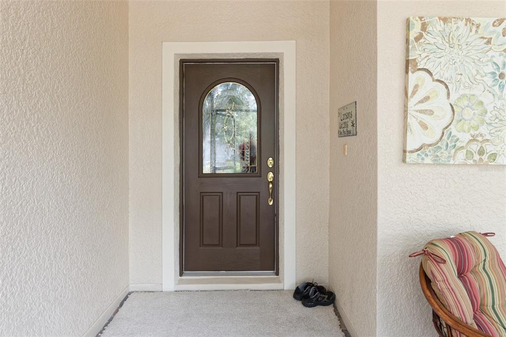 A brown front door with a glass insert sits in a beige entryway with carpet — 105 CUPOLA LOOP, KISSIMMEE, FL