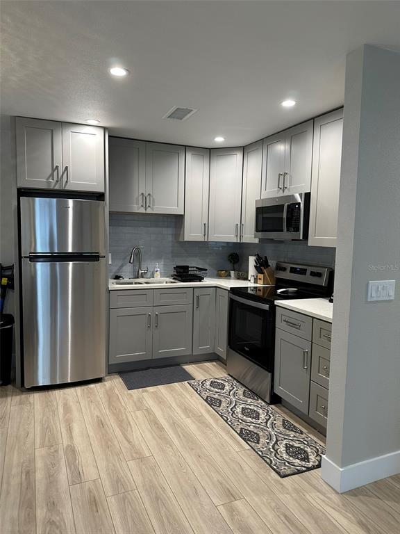 A kitchen features gray cabinets, stainless steel appliances, and light wood-look flooring — 1840 3RD AVENUE E, BRADENTON, FL