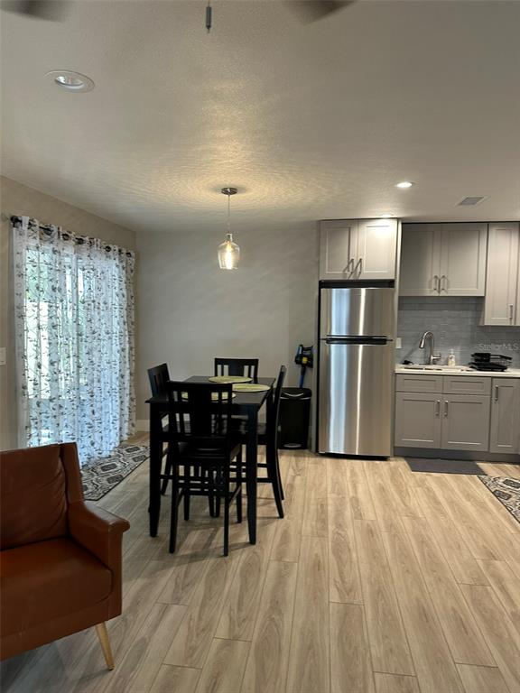 A dining area with a table and chairs sits adjacent to a kitchen with gray cabinets — 1840 3RD AVENUE E, BRADENTON, FL