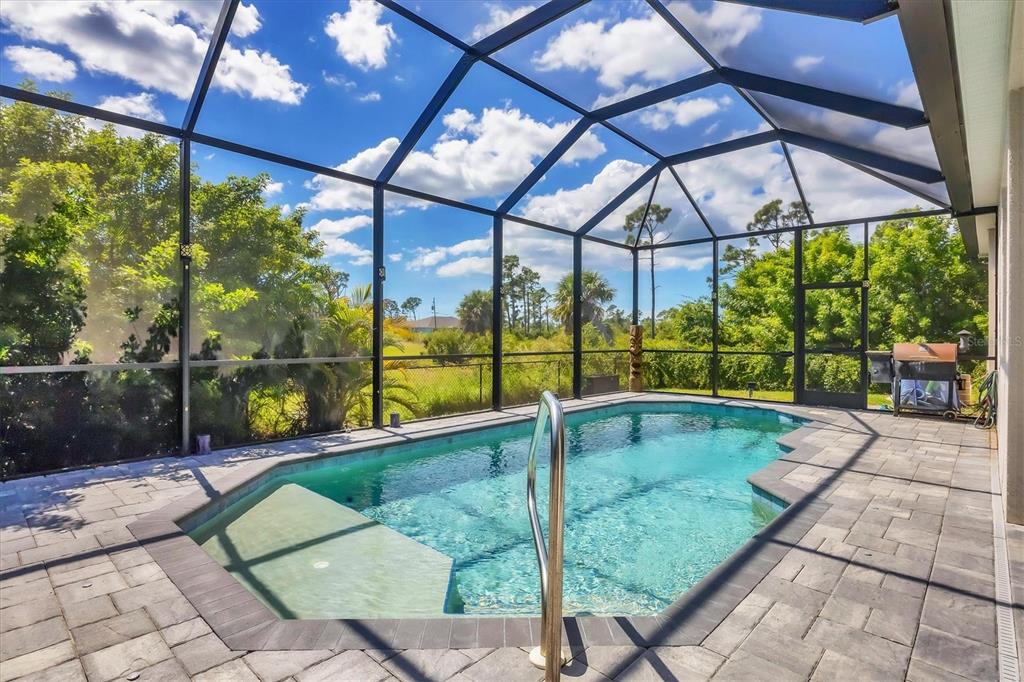An aerial view shows a house with a screened pool next to a vacant lot — 11 LATEEN SAIL DRIVE, PLACIDA, FL