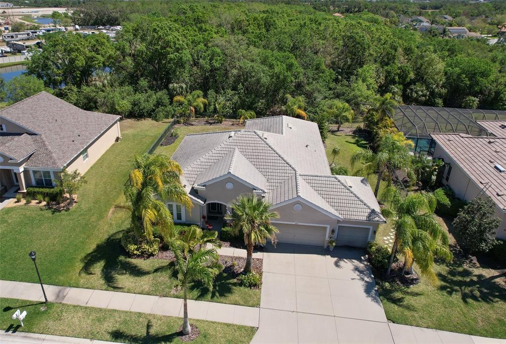 An aerial view shows a single-story house with a tiled roof, driveway, and palm trees — 5409 CONCH SHELL PLACE, APOLLO BEACH, FL