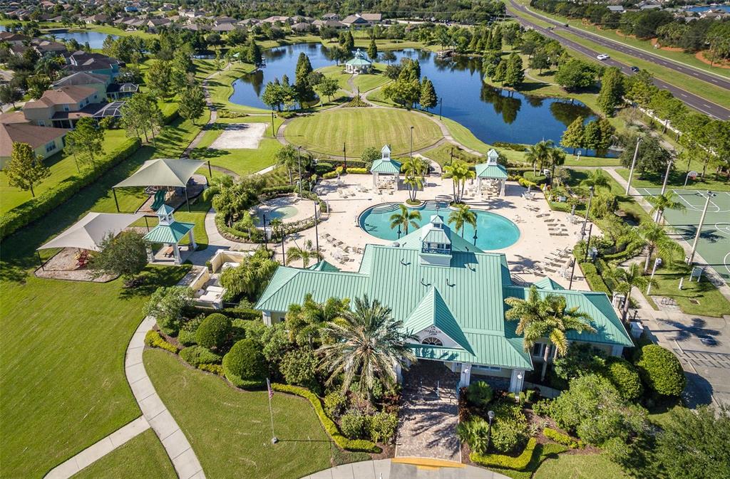 An aerial view of a community clubhouse featuring a swimming pool, playground, and lake — 5409 CONCH SHELL PLACE, APOLLO BEACH, FL
