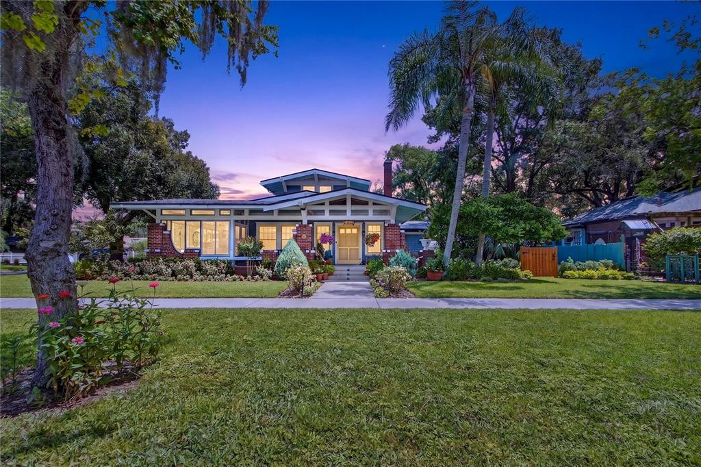 A single-story bungalow with a brick facade, front porch, and palm trees at dusk — 1201 MAGNOLIA AVENUE, SANFORD, FL