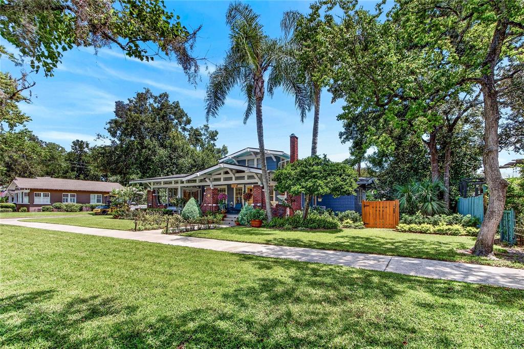 A blue bungalow with a brick chimney and front porch sits behind a grassy lawn — 1201 MAGNOLIA AVENUE, SANFORD, FL