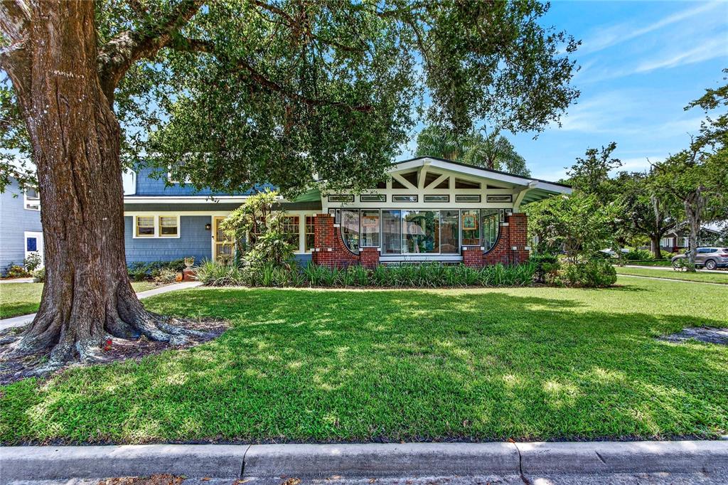 A blue house with a brick-based sunroom and a large tree in the front yard — 1201 MAGNOLIA AVENUE, SANFORD, FL