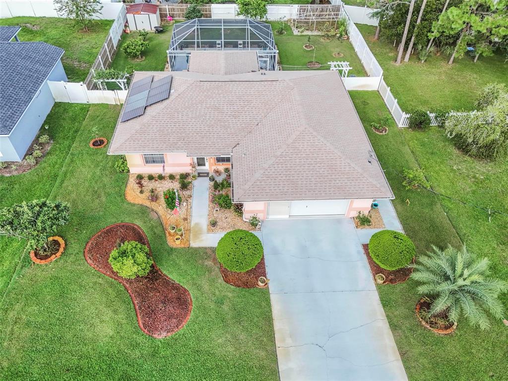 An aerial view of a single-story house with a shingled roof, solar panels, and pool enclosure — 29 WHITTLESEY LANE, PALM COAST, FL