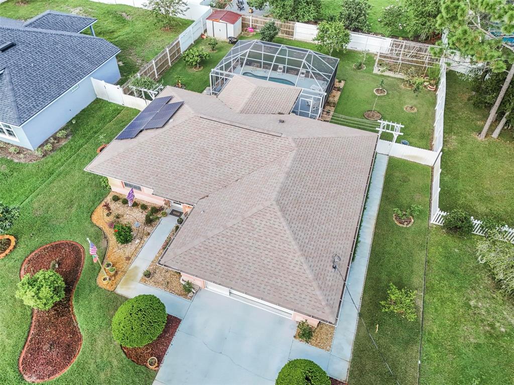 An aerial view shows a house with a shingled roof, solar panels, and a screened pool — 29 WHITTLESEY LANE, PALM COAST, FL