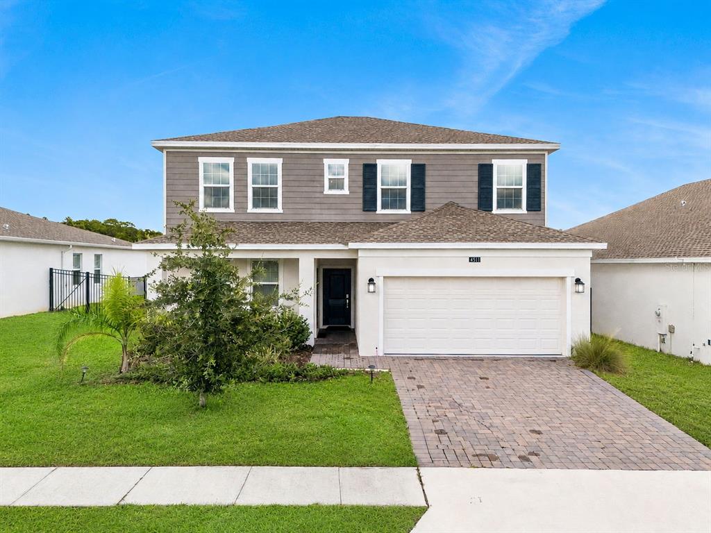 A two-story house with gray siding, a white stucco lower level, and a brick driveway — 4511 HILLINGDAM ROAD, DAVENPORT, FL