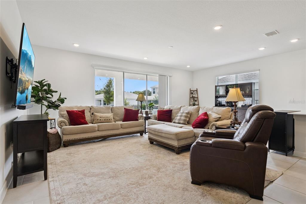 A living room features a beige sectional sofa, a brown recliner, and a wall-mounted television — 4511 HILLINGDAM ROAD, DAVENPORT, FL