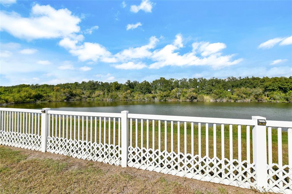 A grassy backyard features a white vinyl fence bordering a line of trees — 7514 FOREST MERE DRIVE, RIVERVIEW, FL