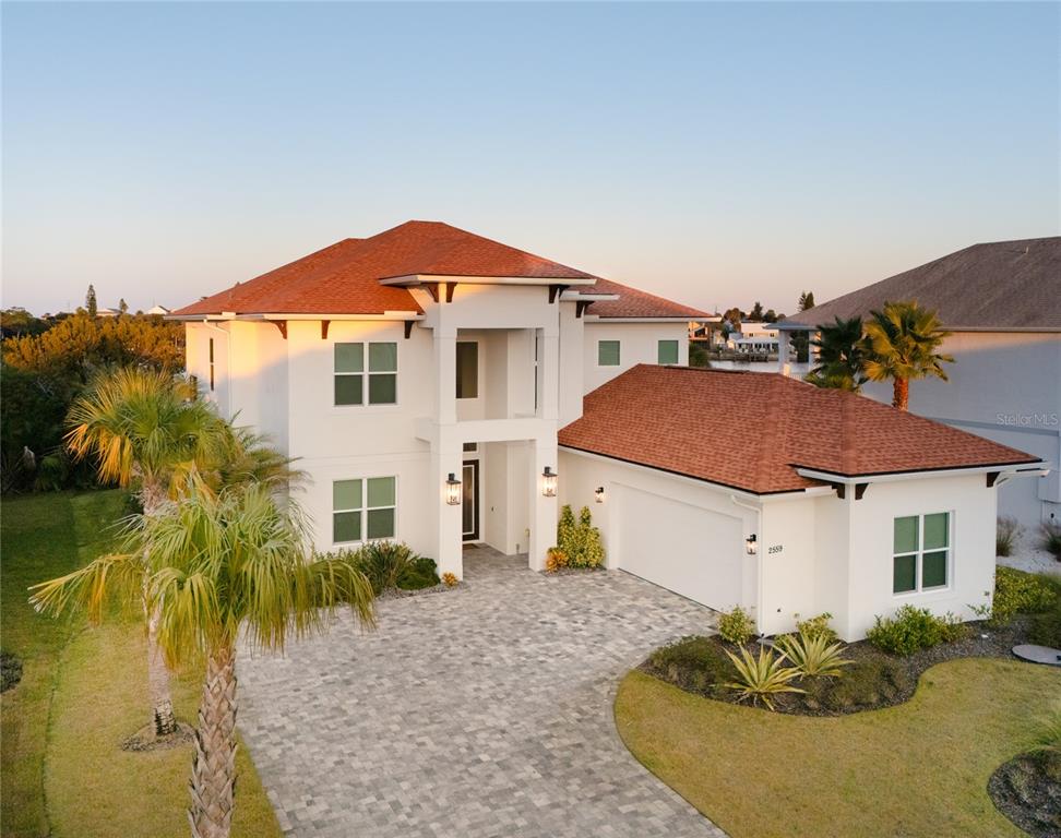 An aerial view of a two-story white house with a red roof and paver driveway — 2559 PALM AVENUE, FLAGLER BEACH, FL