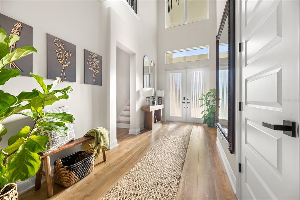 A bright entryway features light wood flooring, a tall mirror, and a staircase — 2559 PALM AVENUE, FLAGLER BEACH, FL