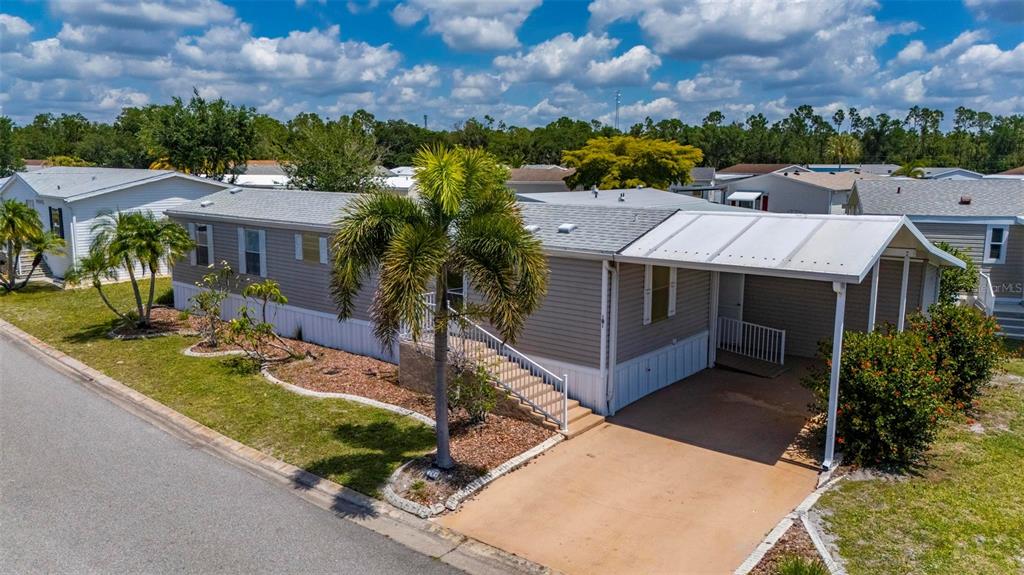 An interior room with light blue walls, gray wood-look flooring, and an open exterior door — 1000 KINGS HIGHWAY UNIT 101, PORT CHARLOTTE, FL