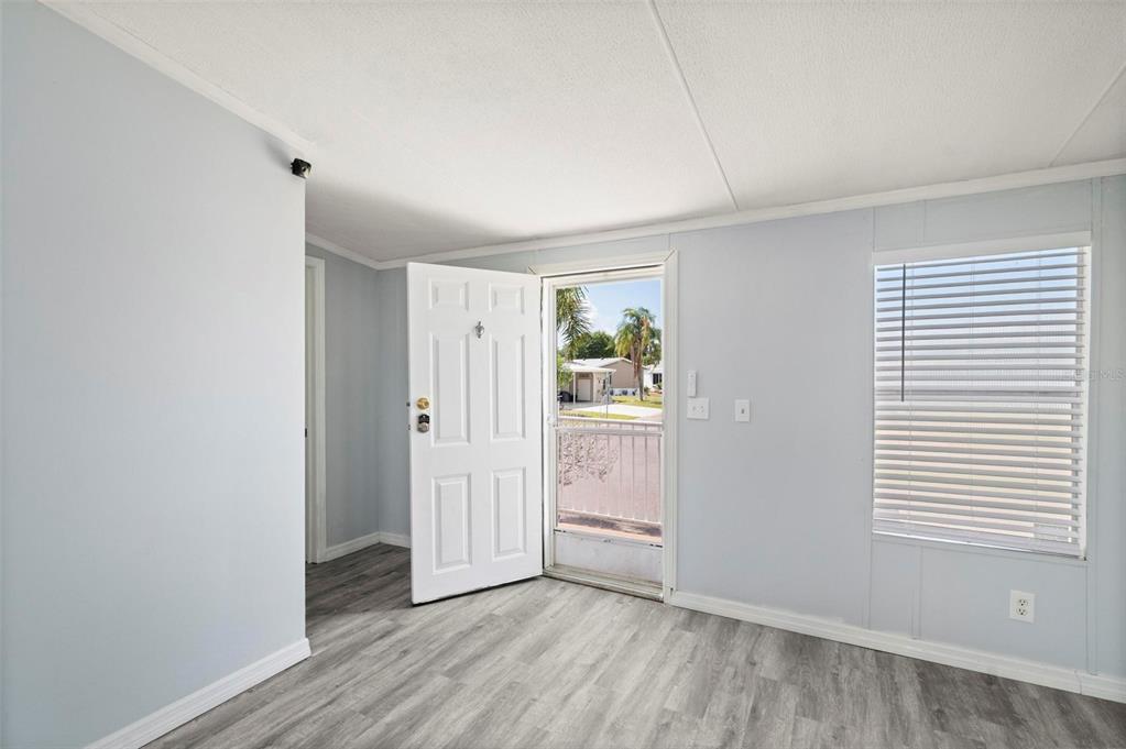 An open-concept living area features light gray walls, wood-look flooring, and an adjacent kitchen — 1000 KINGS HIGHWAY UNIT 101, PORT CHARLOTTE, FL