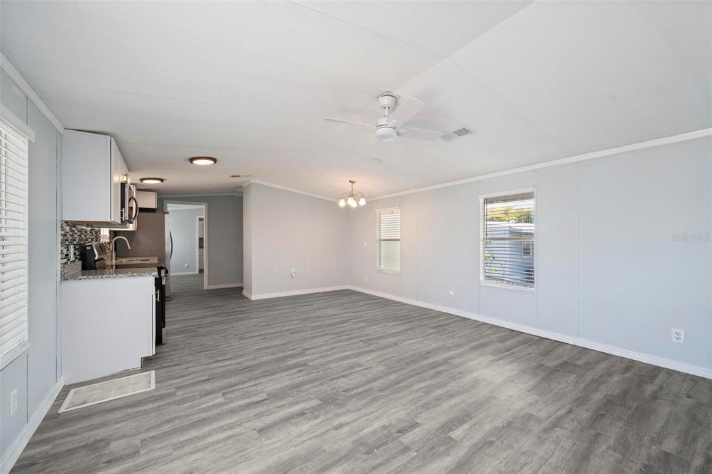 An open-concept kitchen and living area with light gray flooring, white cabinets, and a ceiling fan — 1000 KINGS HIGHWAY UNIT 101, PORT CHARLOTTE, FL