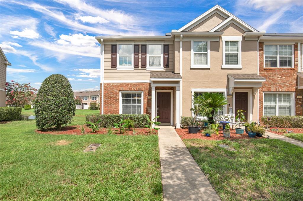 A two-story townhouse with a brick and tan facade, a front walkway, and green lawn — 6544 ARCHING BRANCH CIRCLE, JACKSONVILLE, FL
