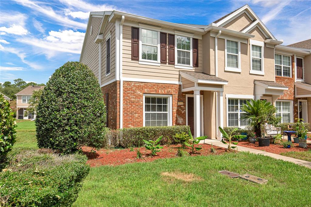 A two-story townhouse with a brick and tan siding exterior, a front porch, and landscaping — 6544 ARCHING BRANCH CIRCLE, JACKSONVILLE, FL
