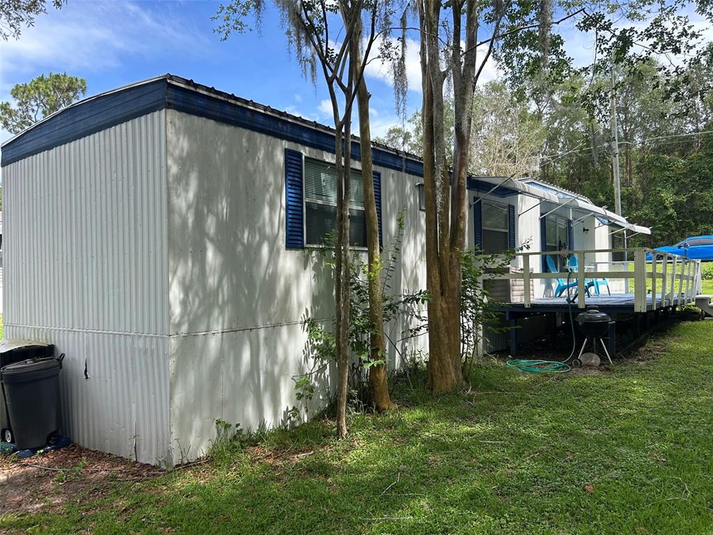A living room features wood-paneled walls, a tan sofa, and a folding chair — 10945 SE 132ND PLACE, OCKLAWAHA, FL