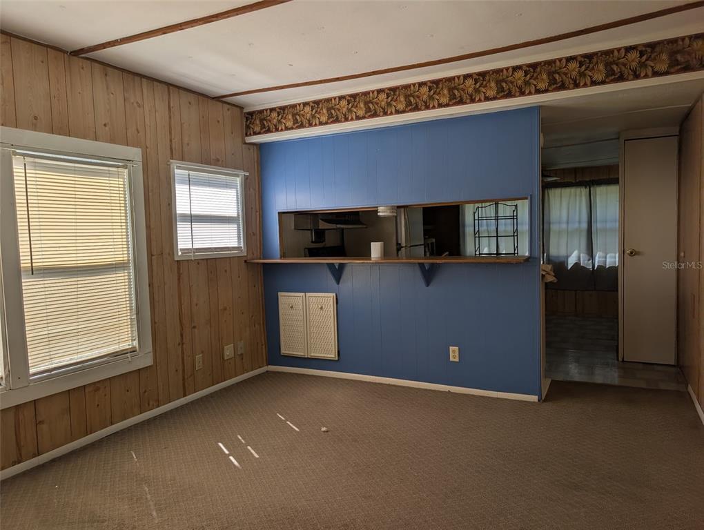 A kitchen features wood-paneled walls, white lower cabinets, glass-front upper cabinets, and a sink — 10945 SE 132ND PLACE, OCKLAWAHA, FL