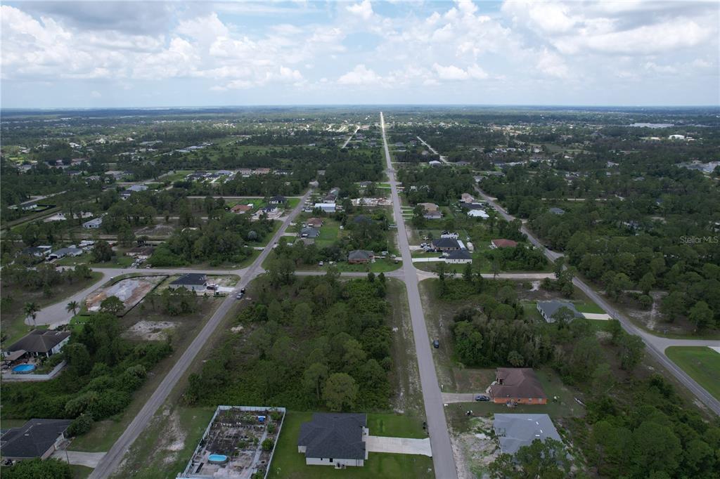 An aerial view shows a residential neighborhood with scattered houses and undeveloped lots — 1056 JAGUAR BOULEVARD, LEHIGH ACRES, FL