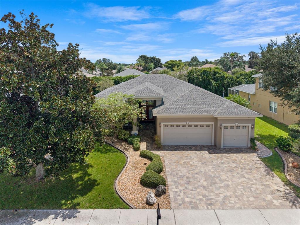 An aerial view of a single-story house with a paver driveway and a three-car garage — 2313 EDELWEISS LOOP, TRINITY, FL