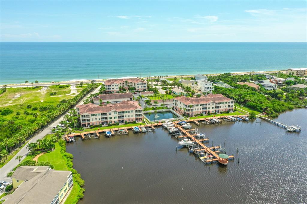 An aerial view shows waterfront apartment buildings with a private marina and boat slips — 300 MARINA BAY DRIVE UNIT 106, FLAGLER BEACH, FL
