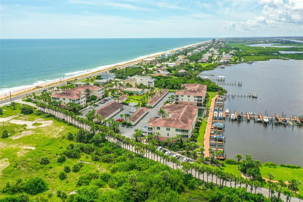 An aerial view shows a coastal condominium complex with a marina beside a large body — 300 MARINA BAY DRIVE UNIT 106, FLAGLER BEACH, FL